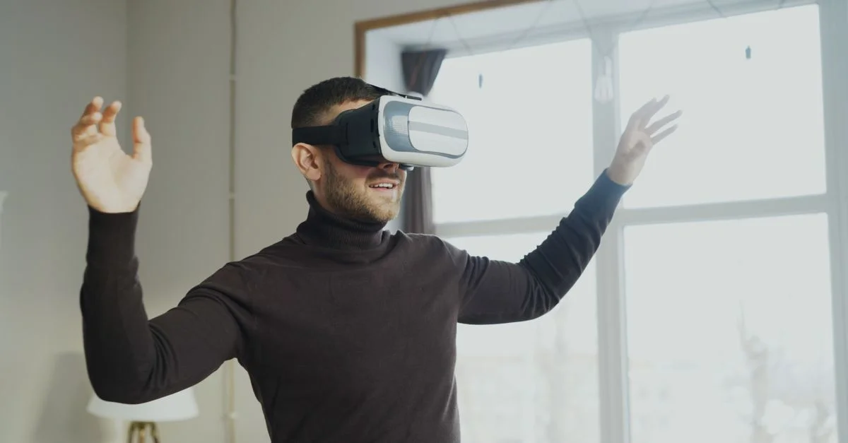 Un homme portant des lunettes de réalité virtuelle, gesticulant avec enthousiasme à l'intérieur.