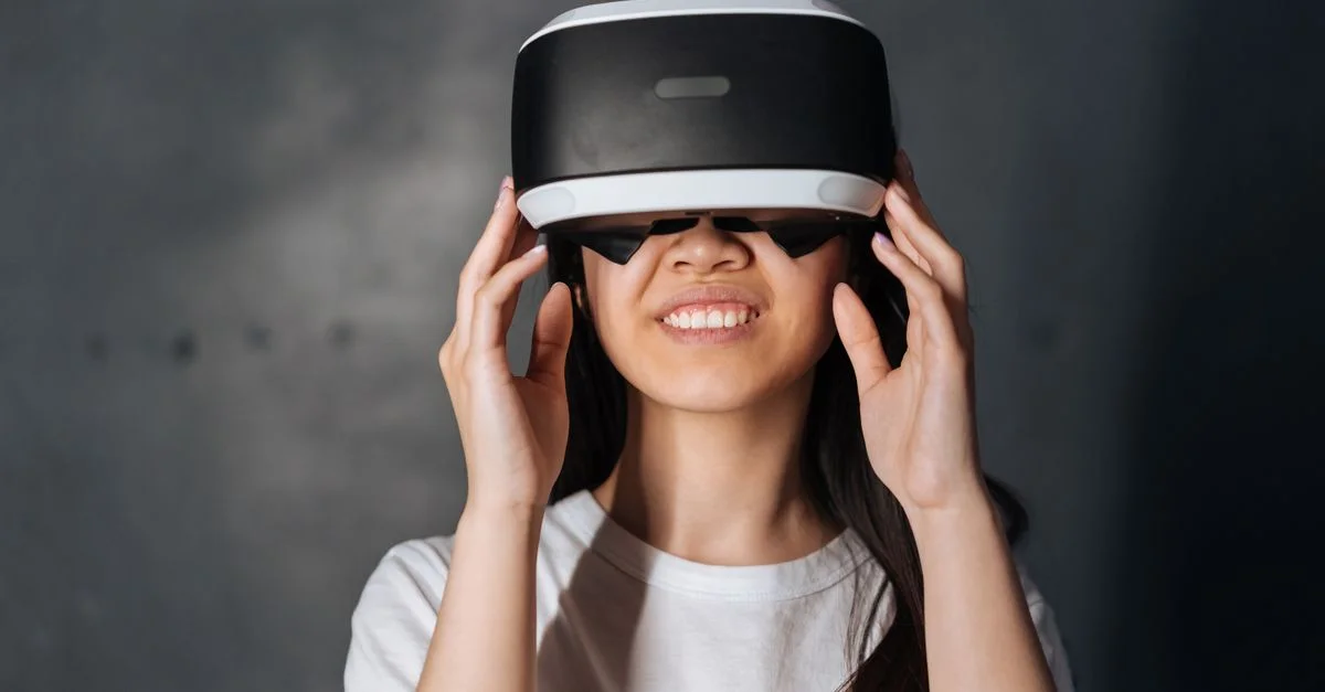 Jeune femme souriante plongée dans la réalité virtuelle, portant un casque VR à l'intérieur.