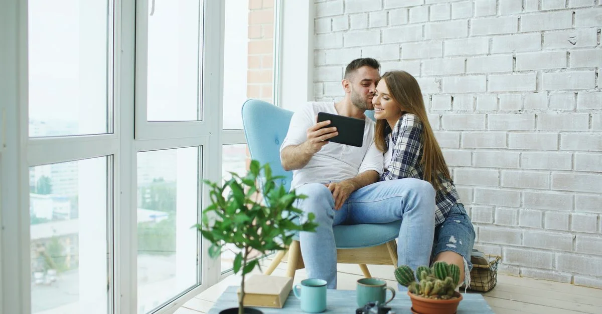 Un couple heureux assis dans un intérieur lumineux, profitant de leur temps libre avec une tablette.