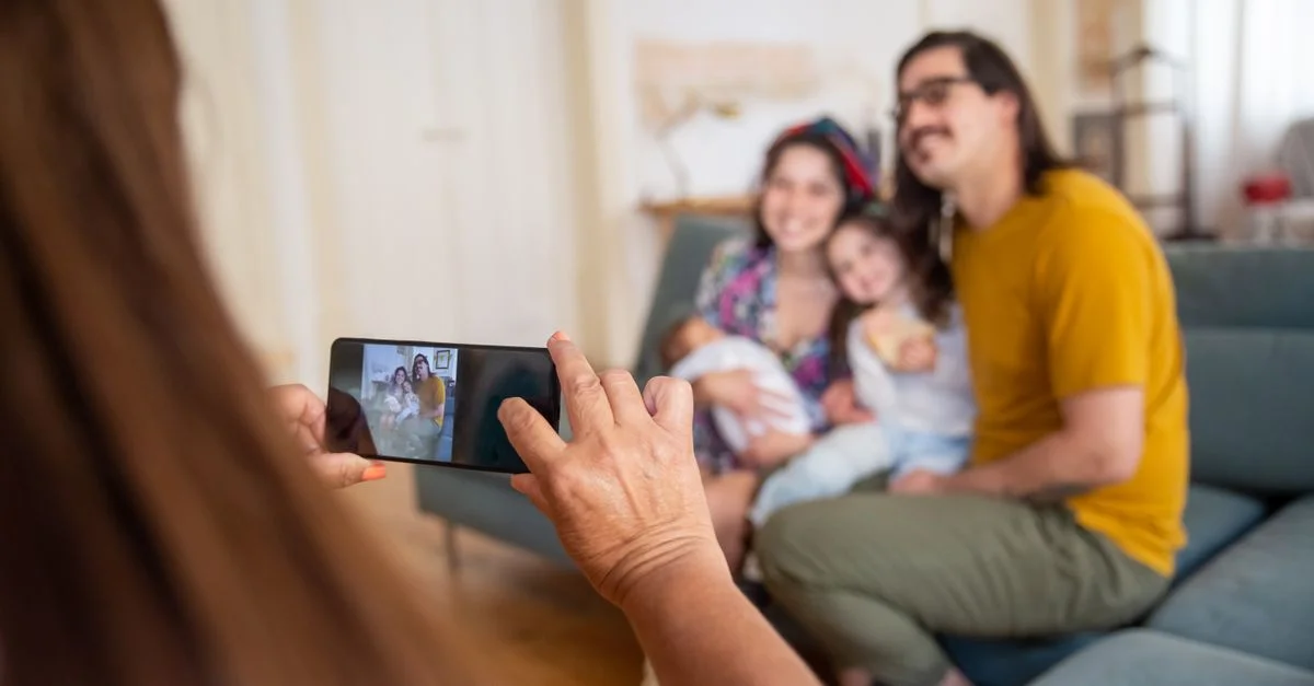 Une famille pose pour une photo avec un smartphone à l'intérieur, capturant un moment joyeux ensemble.