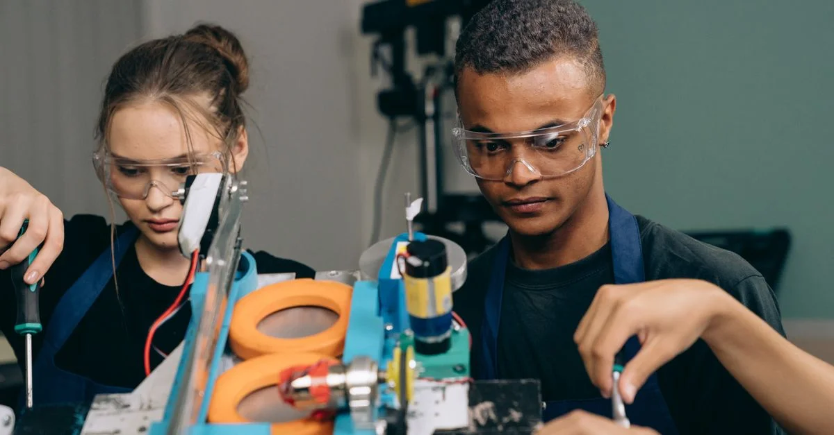 Deux jeunes ingénieurs se concentrant sur un projet de robotique à l'intérieur, illustrant le travail d'équipe et la technologie.
